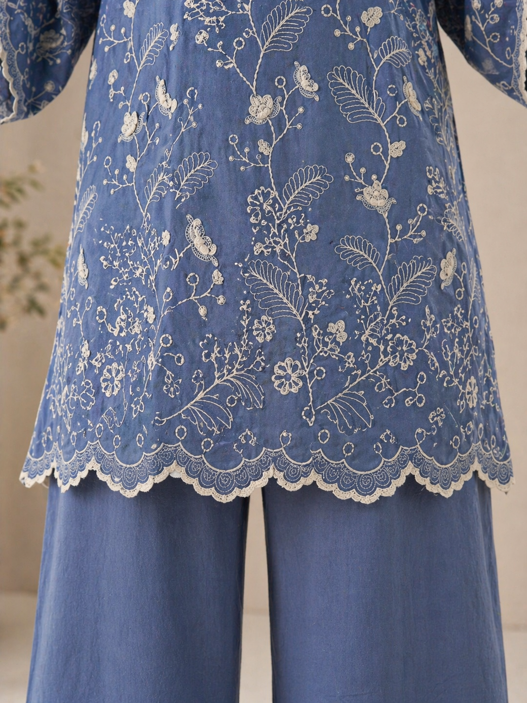 Detailed view of floral embroidery and scalloped lace border on kurta hem, highlighting fine craftsmanship and elegant finishing.